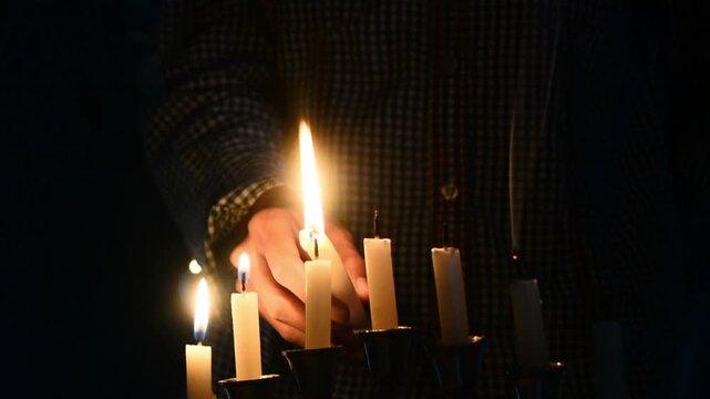 Hanukkah celebration candles glowing on a black background with warm festive light. Traditional Jewish holiday decoration featuring menorah candle flames, spiritual atmosphere, cultural symbolism, and