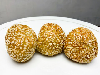 Close-up view, Indonesian traditional food called onde onde sprinkled with sesame has a golden color and a round shape while placed on a white plate