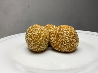 Close-up view, Indonesian traditional food called onde onde sprinkled with sesame has a golden color and a round shape while placed on a white plate