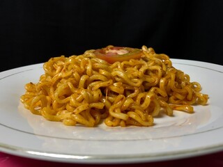 The display of Indonesian fried noodles on a white plate with a black background