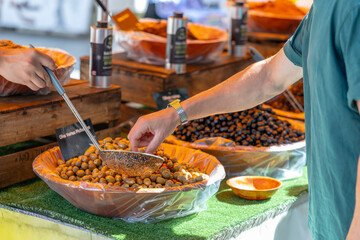 Customer Choosing Olives at a French Market in Nyons, France