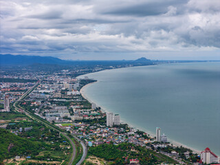 Fototapeta premium Aerial drone shot of Hua Hin city and Khao Takiab Nuea Beach under cloudy rainy season sky, favored by expats over 50