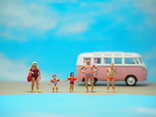 Mini toy of action figure at table with blurred background. Toy photography concept design. Surfer man at outdoor. Recreation refreshing vacation summer holiday and water sport concept with camper van