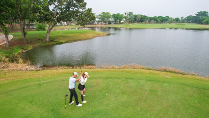 Drone view of young golfers swing clubs together on a scenic golf course. 