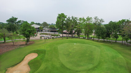 Drone view of golf course with wide lush green fairway and sand bunker. 