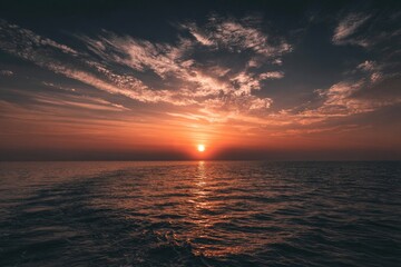 Obraz premium Sunset over a calm sea with dramatic clouds