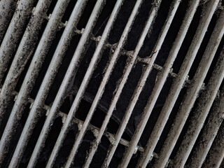 A gritty close-up of a dirty air conditioner or fan vent covered in dust and grime. The image highlights a need for cleaning, representing poor air quality or maintenance issues