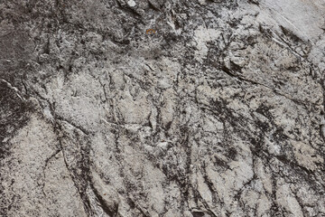 Close Up Texture Background Of A Weathered And Grungy Grey Rock Surface With Dark Patches and Cracks. Natural Stone Pattern.