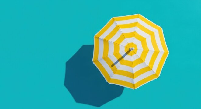 Top view of a yellow and white striped beach umbrella on a bright blue surface