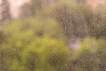 Close-up photo of rain droplets on a glass window with warm light tones. Abstract texture background in high resolution, perfect for wallpaper or design