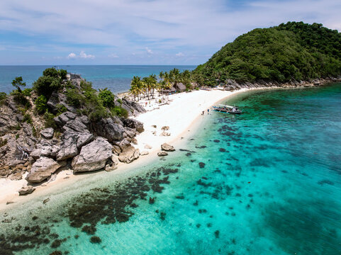 Aerial view of the turquoise waters meeting the white sandy beach and lush green island, a tropical paradise unfolds from above, Caramoan, Camarines Sur, Philippines.