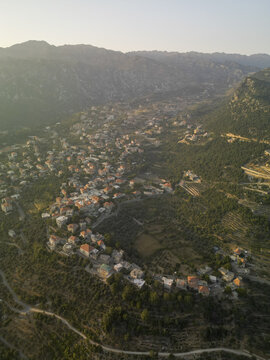 Aerial view of a small town nestled among rolling hills with the sun casting soft shadows, Douma, North Governorate, Lebanon.