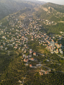 Aerial view of terracotta roofs nestling among the green hills, a tapestry of human habitation woven into the landscape, Douma, North Governorate, Lebanon.