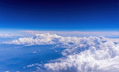 Aerial view of fluffy cumulus clouds covering land under a clear blue sky