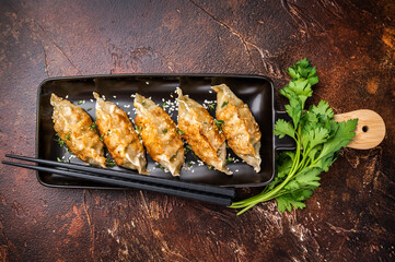 Fried Jiaozi on plate with sauce, Chinese Dumplings with shrimps and vegetables. brown background. top view