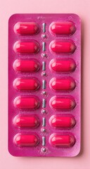 Pink blister pack of oval red capsules, close-up on pink background