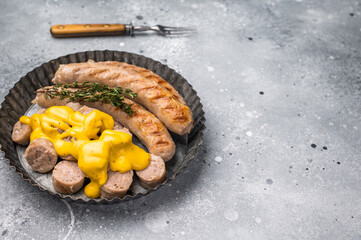 Grilled Bratwurst Sausages with cheese sauce in plate. grey background. top view