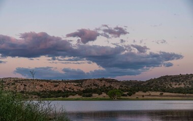 There are fluffy clouds floating in the sky above a serene lake