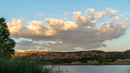 A large cloud floats over a lake with mountains in the background