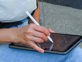 Close-up of a hand writing on a digital tablet with a stylus. © Alex Malt