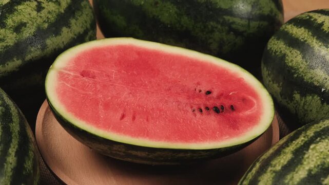 Close-up shot of half pieces of fresh red watermelons on a wooden dish, natural texture background pattern with tropical sweet and nutritious snack in hot summertime, healthy food with abundant fruit.