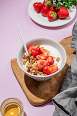 Granola or muesli with natural greek yogurt, strawberry and honey in a bowl on a wooden board