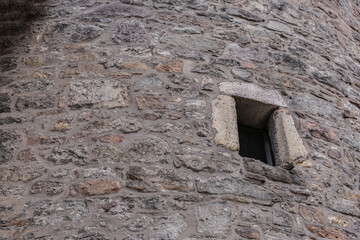 Close up of medieval stone wall with small window in Europe