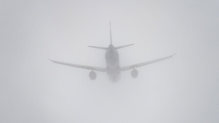 A plane is flying through a foggy sky. The plane is barely visible, and the fog is thick, creating a sense of mystery and uncertainty