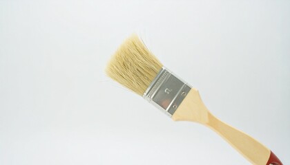 A light beige paintbrush with a light wooden handle sits angled against a plain white background.