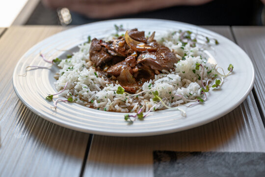 Fried poultry liver on stewed rice on white plate.