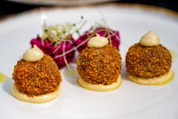 Appetizer, fried breaded duck ball and beetroot ball on plate.