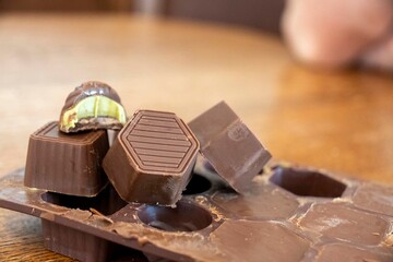 A person is gracefully holding a tray filled with chocolates on a table