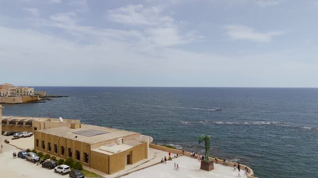Aerial Drone Shot Approaching Mitoraj Sculpture On Isola Di Ortigia In Syracuse, Sicily, Italy On A Bright Summer Day.