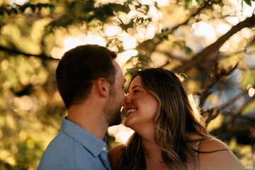 Fototapeta premium Young couple sharing a romantic kiss outdoors in warm evening sunlight, symbolizing love, intimacy, and happiness. Perfect for lifestyle, relationship, and Valentine themes.