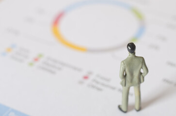 Businessman Figurine Analyzing Pie Chart for Strategic Decision