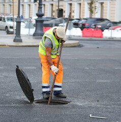 A road worker cleans a manhole from dirt, Nevsky Prospekt, Saint Petersburg, Russia, August 18, 2025