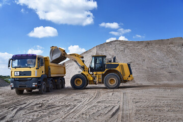 Wheel loader loads a truck with sand in a gravel pit