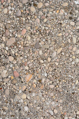 A full-frame, high-angle view of a concrete surface with various small, light-colored pebbles and gravel, creating a textured background