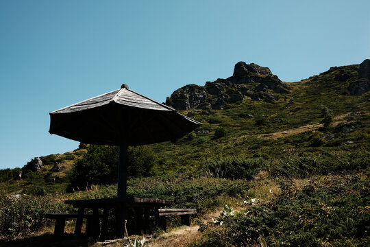 Wooden shelter and benches with view of Stara Planina rocky peaks under clear blue sky. Babin Zub mount in summer season