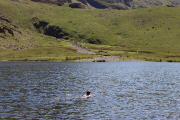 Woman wild swimming in a Lake District tarn