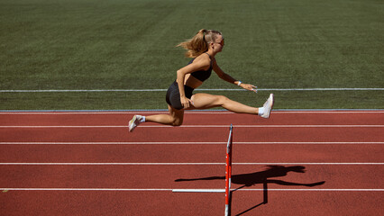 Female hurdler mid-air jumping hurdle on track. Concept of overcoming barriers, strength in motion, determination, resilience, and pushing limits in athletics.