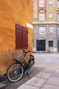 Bicycle with basket near ochre building in Nyboder Copenhagen Denmark, combining historic architecture, cultural identity, urban charm and cycling lifestyle tradition