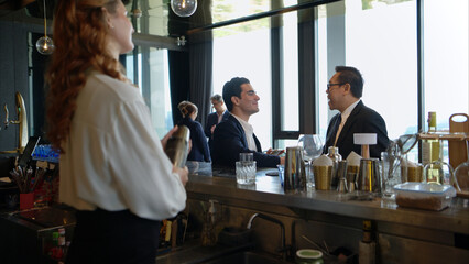 Smiling bartender serving drinks to customers at a modern bar