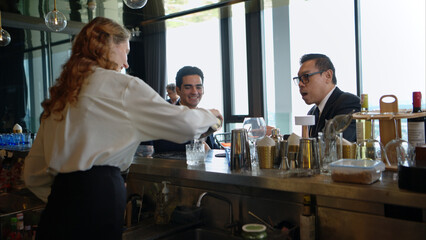 Smiling bartender serving drinks to customers at a modern bar