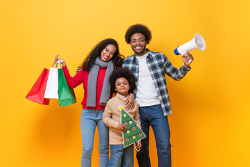 Fototapeta premium Happy African American family in festive Christmas celebration concept, studio shot on yellow color isolated background