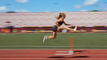 Dynamic blurred shot of female hurdler mid-air during race on stadium track. Concept of athleticism, speed, determination, race competition, and outdoor performance. © Lustre Art Group 