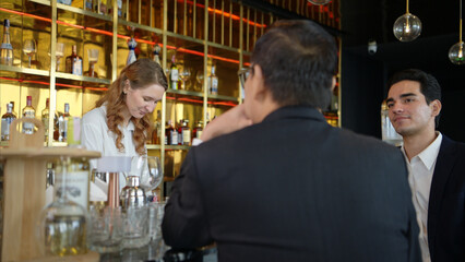 Smiling bartender serving drinks to customers at a modern bar