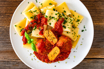 Pasta with meatballs in bolognese sauce on wooden table	