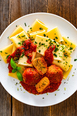 Pasta with meatballs in bolognese sauce on wooden table	