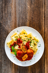 Pasta with meatballs in bolognese sauce on wooden table	
